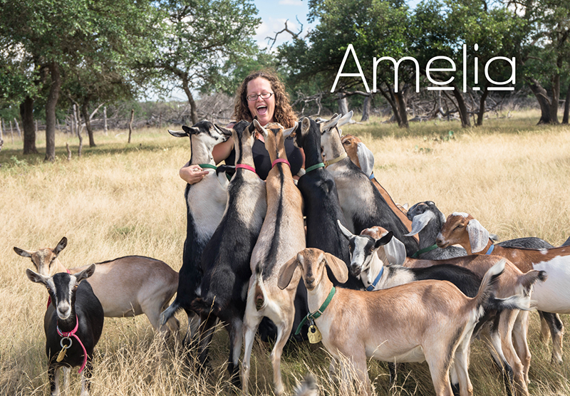 Amelia surrounded by goats on her farm.