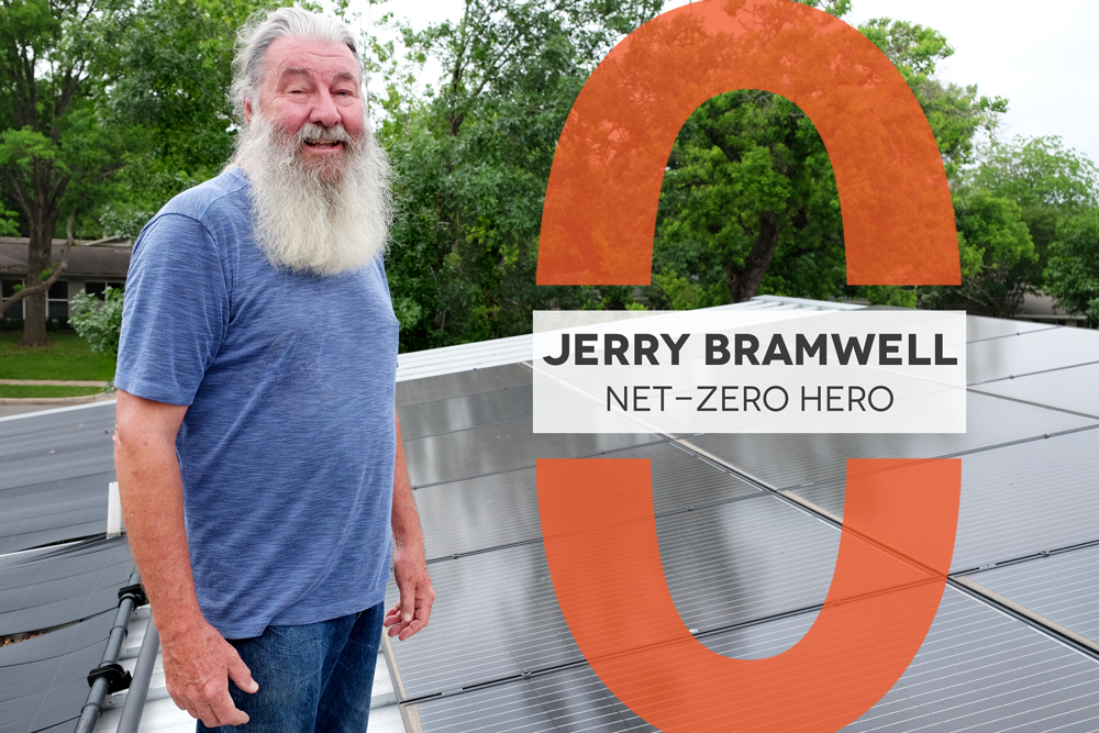 Photo of a man with a long beard wearing a blue t-shirt standing on a roof with solar panels. There is a graphic overlay that reads "Jerry Bramwell Net-Zero Hero"
